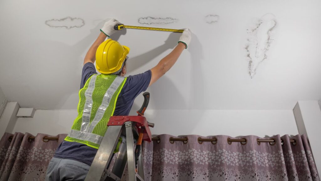 A roofer measuring water damage for a new roof replacement. 